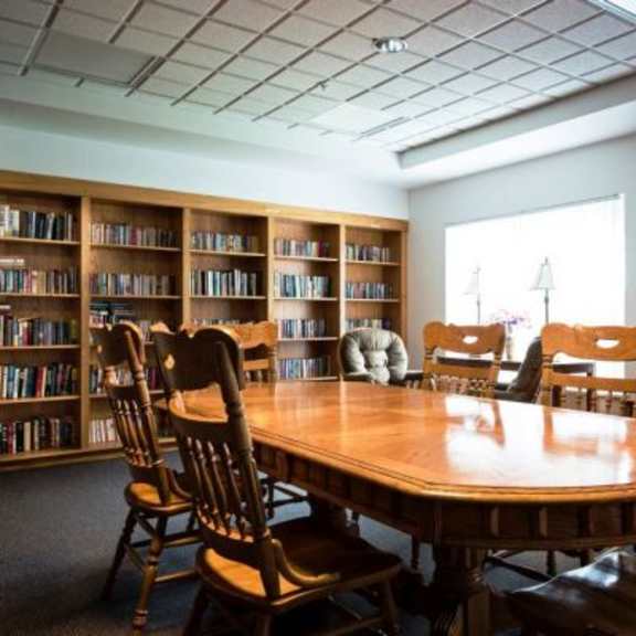a room with a table, chairs, and bookshelves.