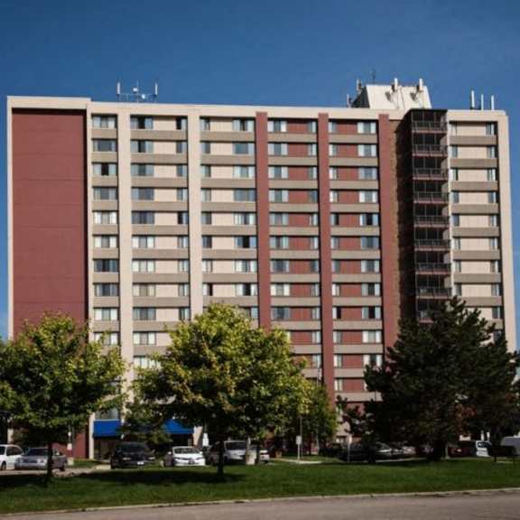 a large multi-story building with a parking lot in front.