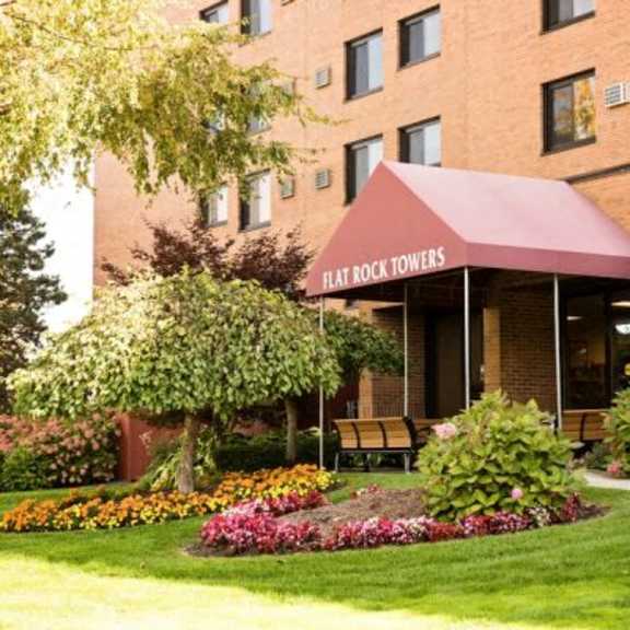 hat rock towers is a hotel with a red awning and a well-maintained garden in front.