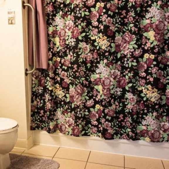 a toilet is in a small bathroom with a floral shower curtain.