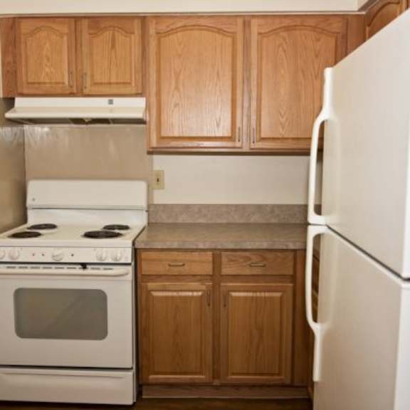 a white stove and refrigerator in a kitchen with wooden cabinets.