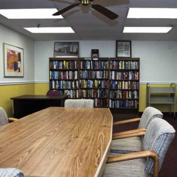 a room with a table, chairs, and a bookshelf filled with books.