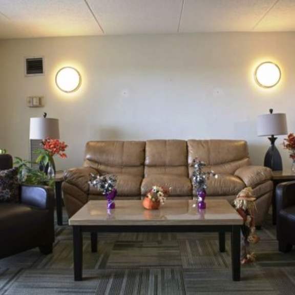 a living room with a brown couch, two chairs, and a coffee table.