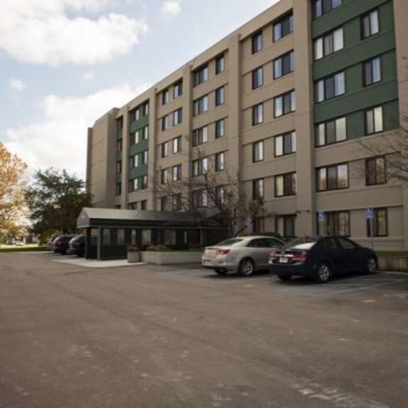 a parking lot in front of a multi-story building with cars parked.