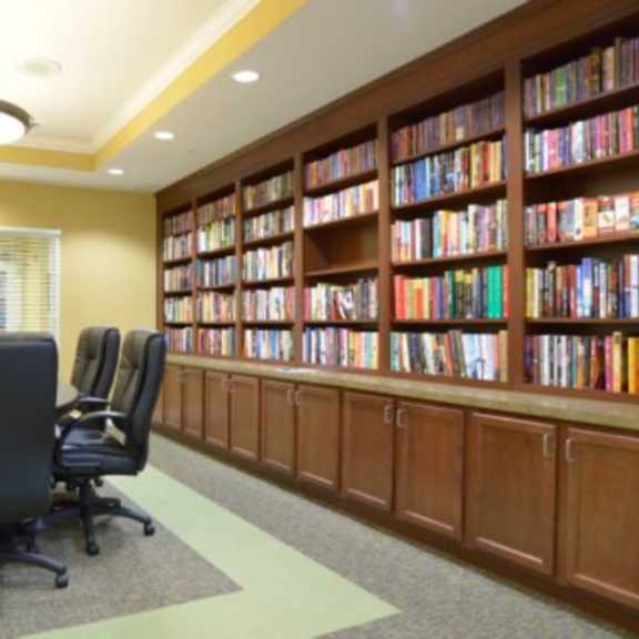 a room with a table and chairs and a bookshelf filled with books.