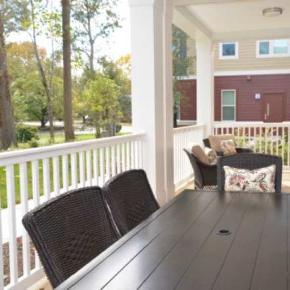 a black table is surrounded by chairs on a porch.