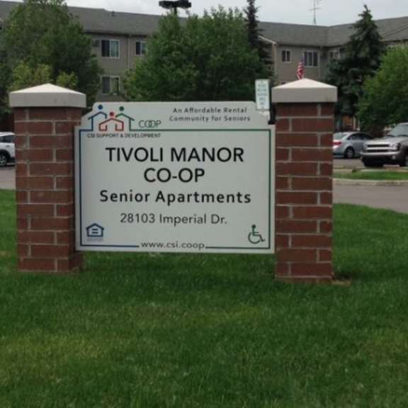 a sign for tivoli manor co-op senior apartments stands in front of a grassy area.