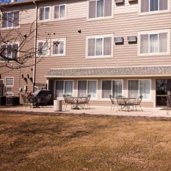 a large apartment building with a patio and chairs.