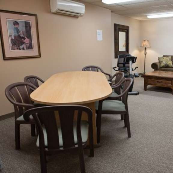 a room with a table, chairs, couch, and a lamp.