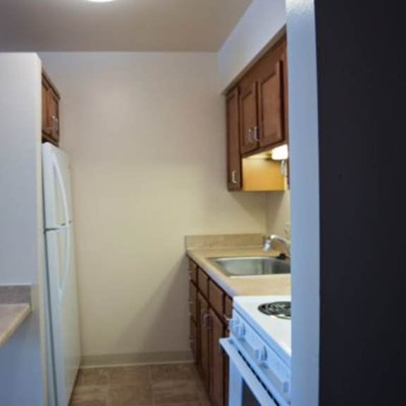 a kitchen with a white refrigerator, brown cabinets, and a white stove top oven.