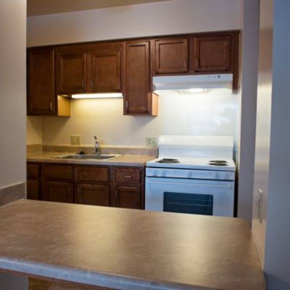 a kitchen with a white stove top oven and brown cabinets.