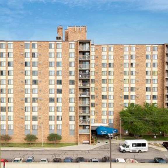 a large brick apartment building with a parking lot in front.