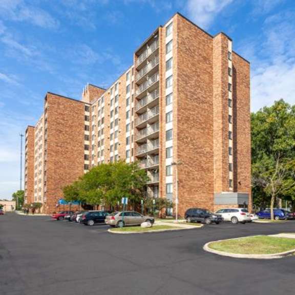 a parking lot in front of a brick apartment building.