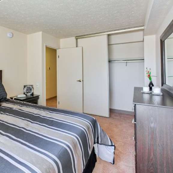 a bedroom with a bed, nightstand, and closet.