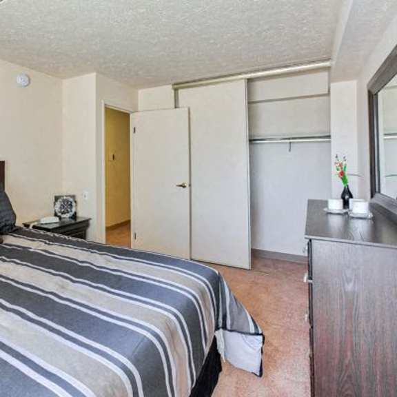 a bedroom with a bed, nightstand, and closet.