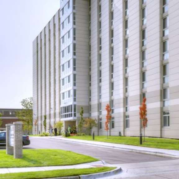 a tall building with many windows is surrounded by a grassy area.