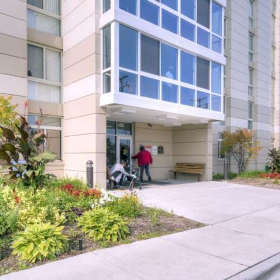 a man in a red shirt is pushing a stroller in front of a building.