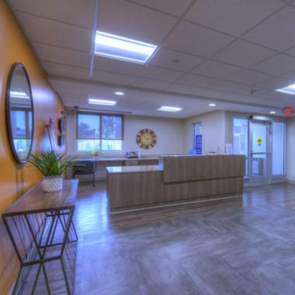 a reception area with a wooden desk and a clock on the wall.