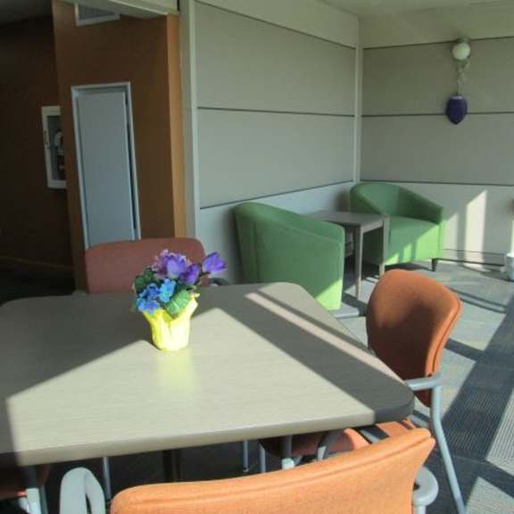 a table with a vase of flowers on it sits in a room with chairs and a door.