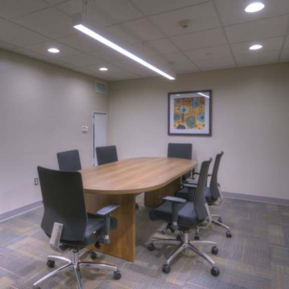 a conference room with a wooden table and black chairs.