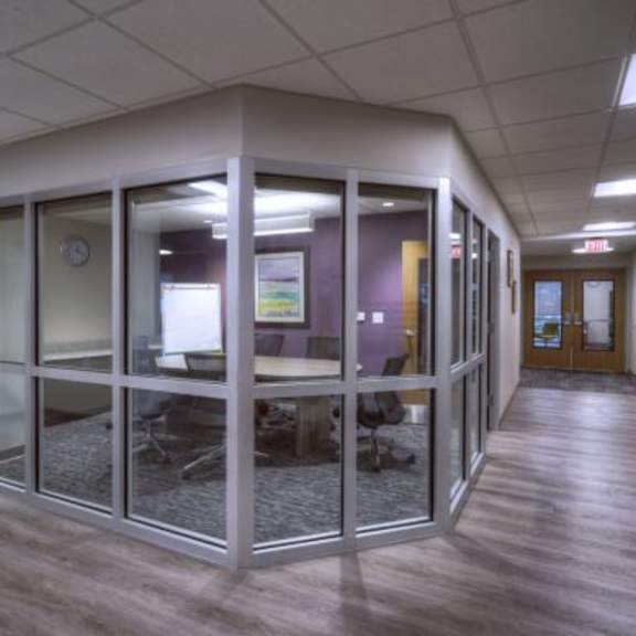 a hallway with glass walls and wooden floors.