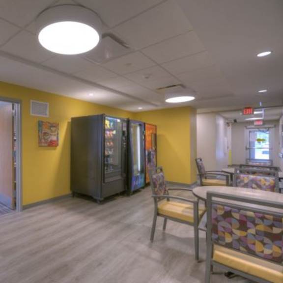 a yellow wall with a vending machine and a chair.