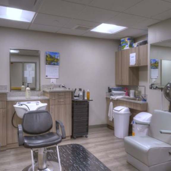 a room with a chair, sink, and mirror.