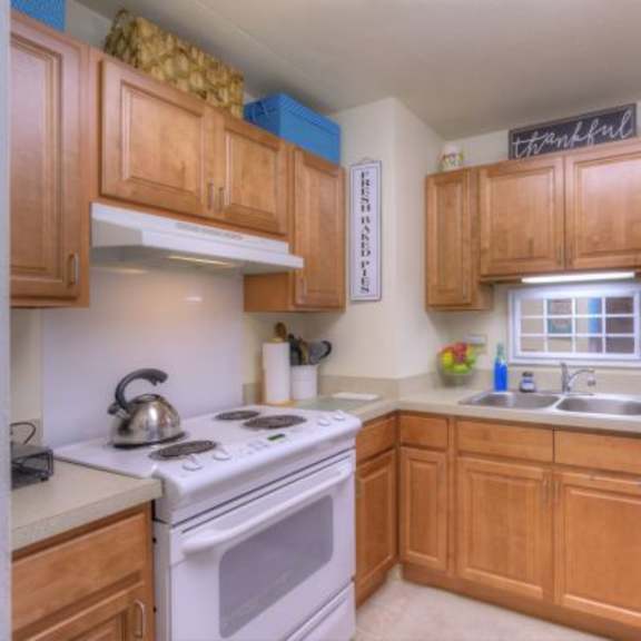 a kitchen with wooden cabinets and a white stove top oven.