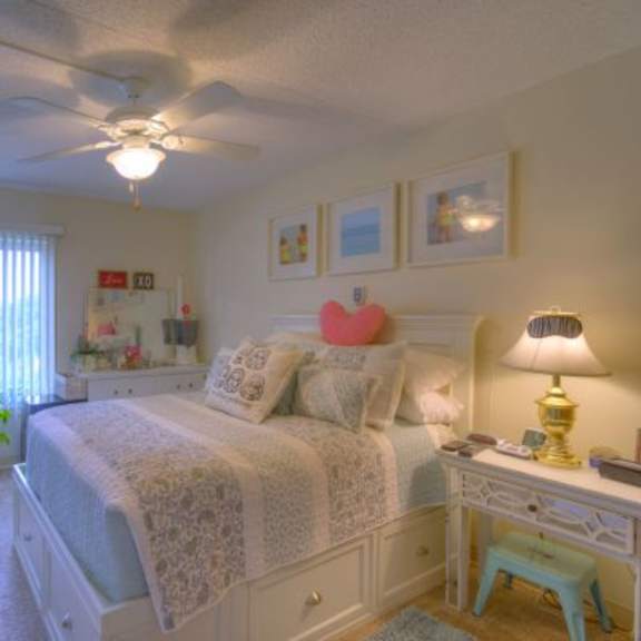 a bedroom with a bed, desk, and ceiling fan.