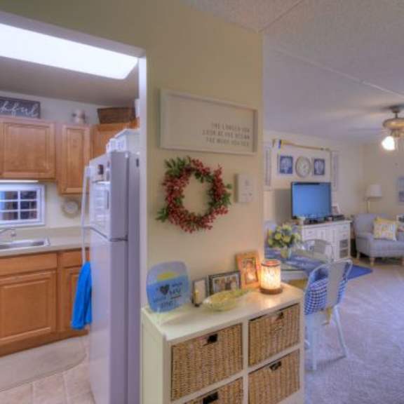 a kitchen with a refrigerator, a dining table with chairs, and a living room with a couch.