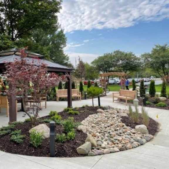 a gazebo is surrounded by benches and a circular garden with rocks in the center.