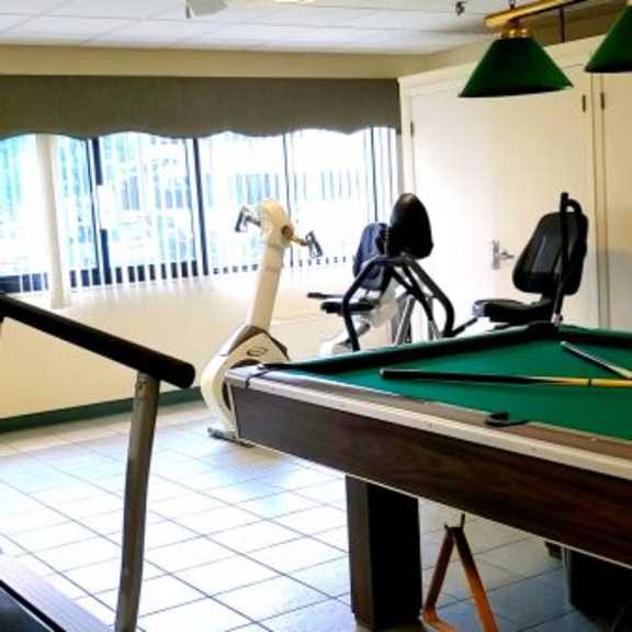 a room with a pool table, treadmill, and exercise equipment.