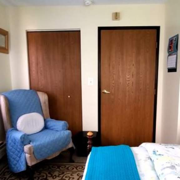 a blue chair sits in a room with a bed and a door.