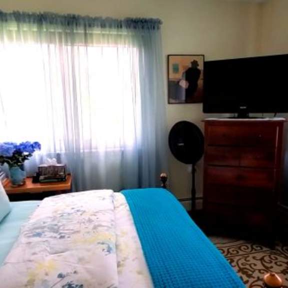 a bedroom with a bed, a television, and a lamp.
