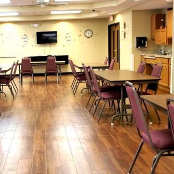 a room with tables and chairs and a tv on the wall.