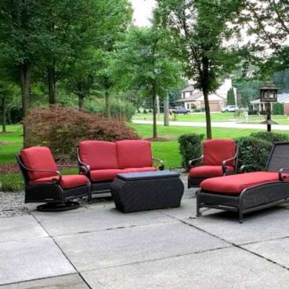 a set of red and black outdoor chairs and tables are arranged on a patio.