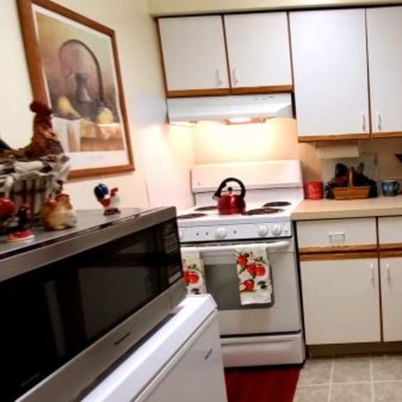a kitchen with a black microwave, white oven, and white fridge.