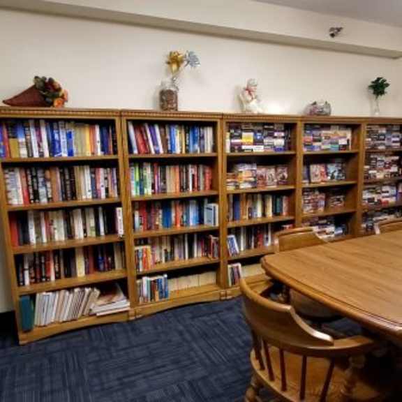 a room with a large bookshelf filled with books and a table with chairs.