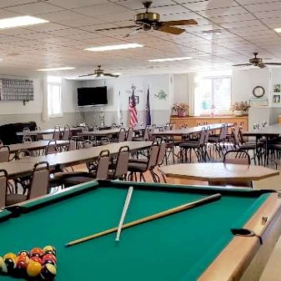 a pool table is in the middle of a room with tables and chairs.