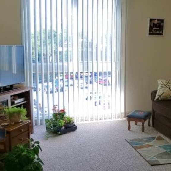 a living room with a couch, a table, and a window with blinds.