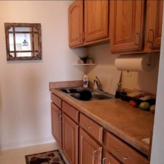 a small kitchen with a white fridge and wooden cabinets.