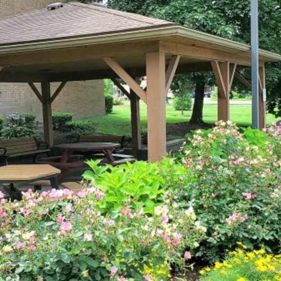 a wooden pavilion with a bench in the middle of a garden.