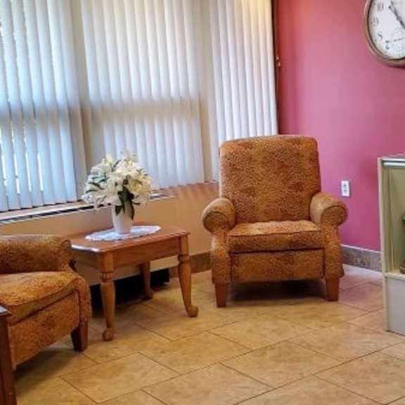 a living room with a couch, chair, and a table with a vase of flowers on it.