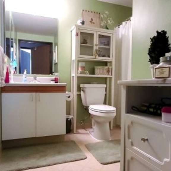 a bathroom with a toilet, sink, and a cabinet with shelves.