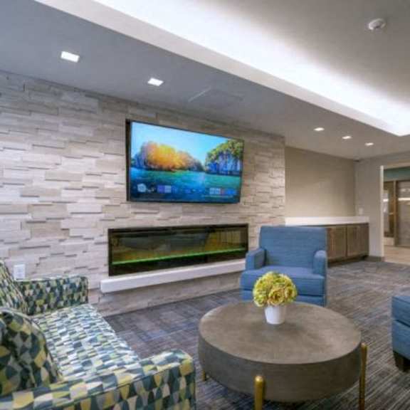 a living room with a stone wall and a flat screen tv.