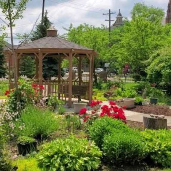 a gazebo is surrounded by greenery and flowers in a park.