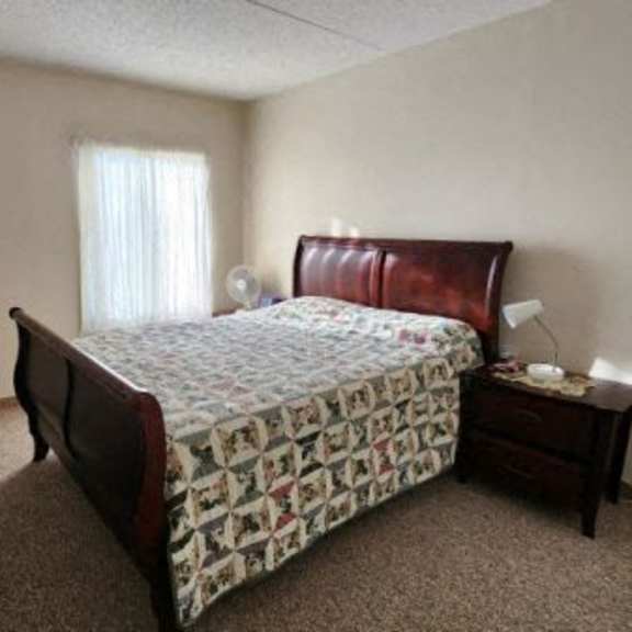 a bedroom with a bed, nightstand, and window.