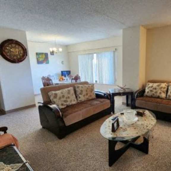a living room with a brown couch, a coffee table, and a lamp.