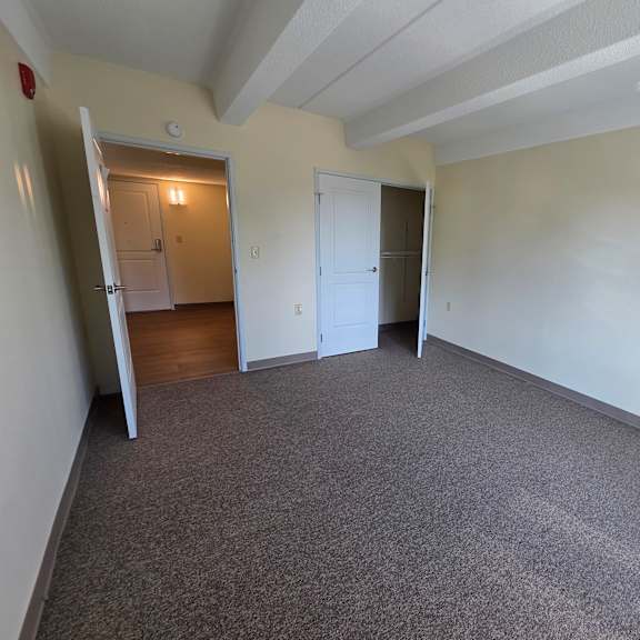 a room with a carpeted floor and two doors.