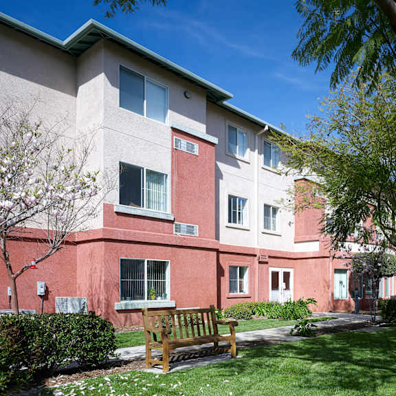 a building with a red and beige exterior has a bench in front of it.
